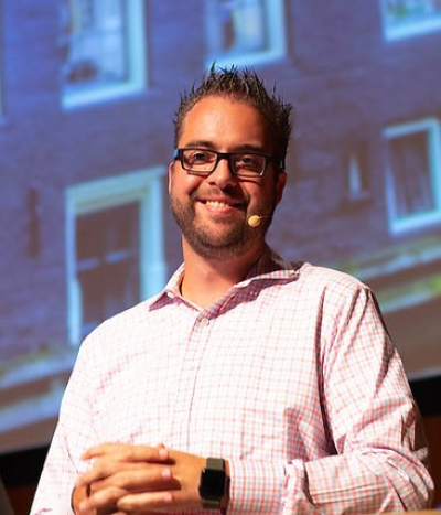 dries, in a pink collared shirt with short brown hair and a beard and glasses